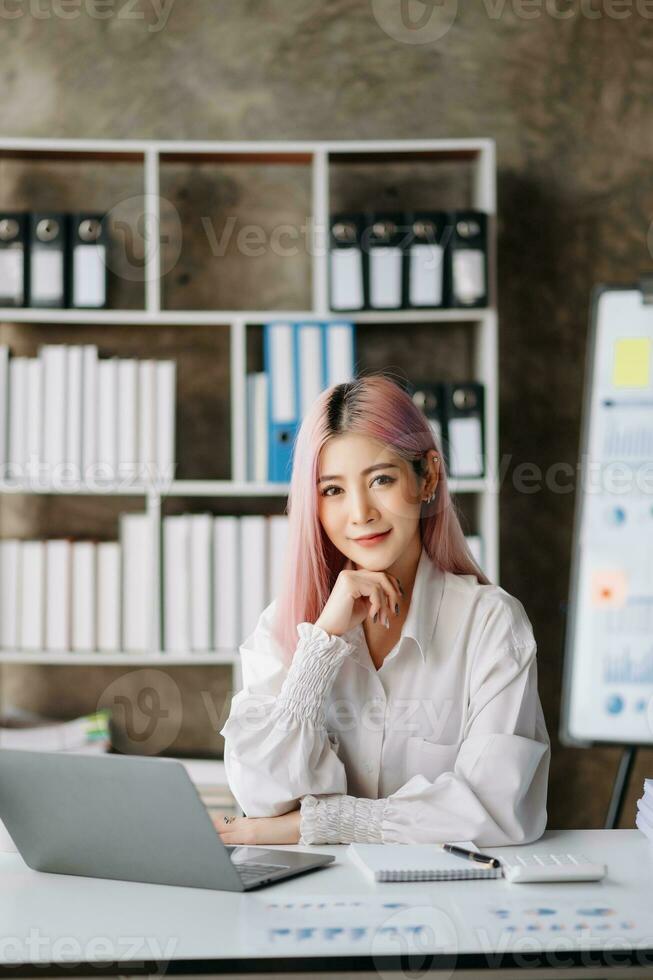 Asian Businesswoman Analyzing Finance on Tablet and Laptop at modern Office Desk tax, report, accounting, statistics, and analytical research concept photo
