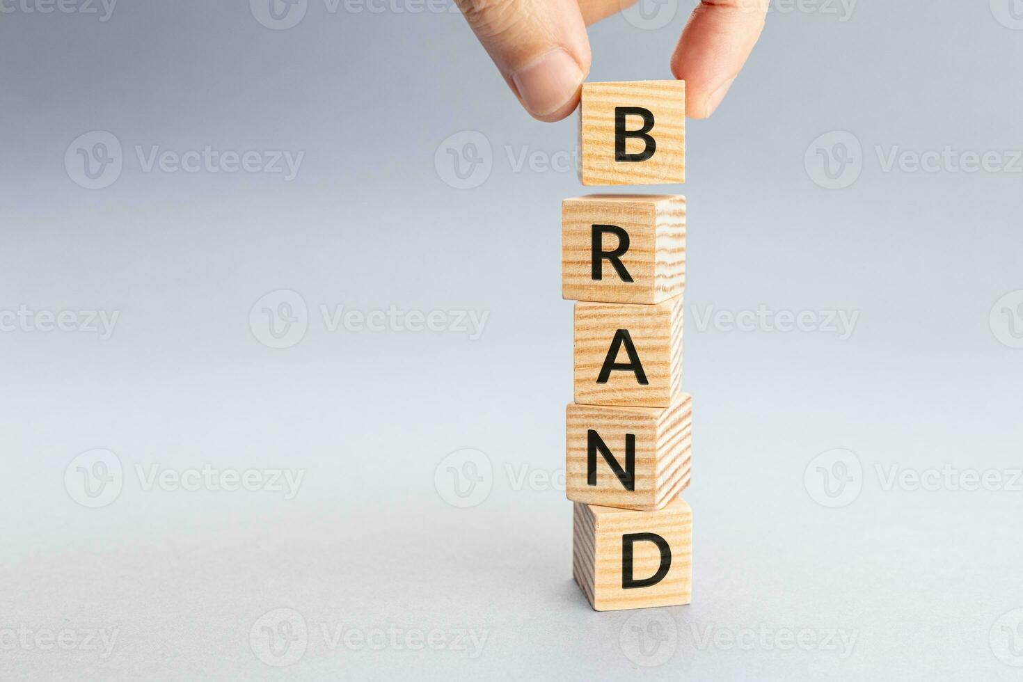 Hand arranging wooden cubes to spell BRAND word. Copy space photo