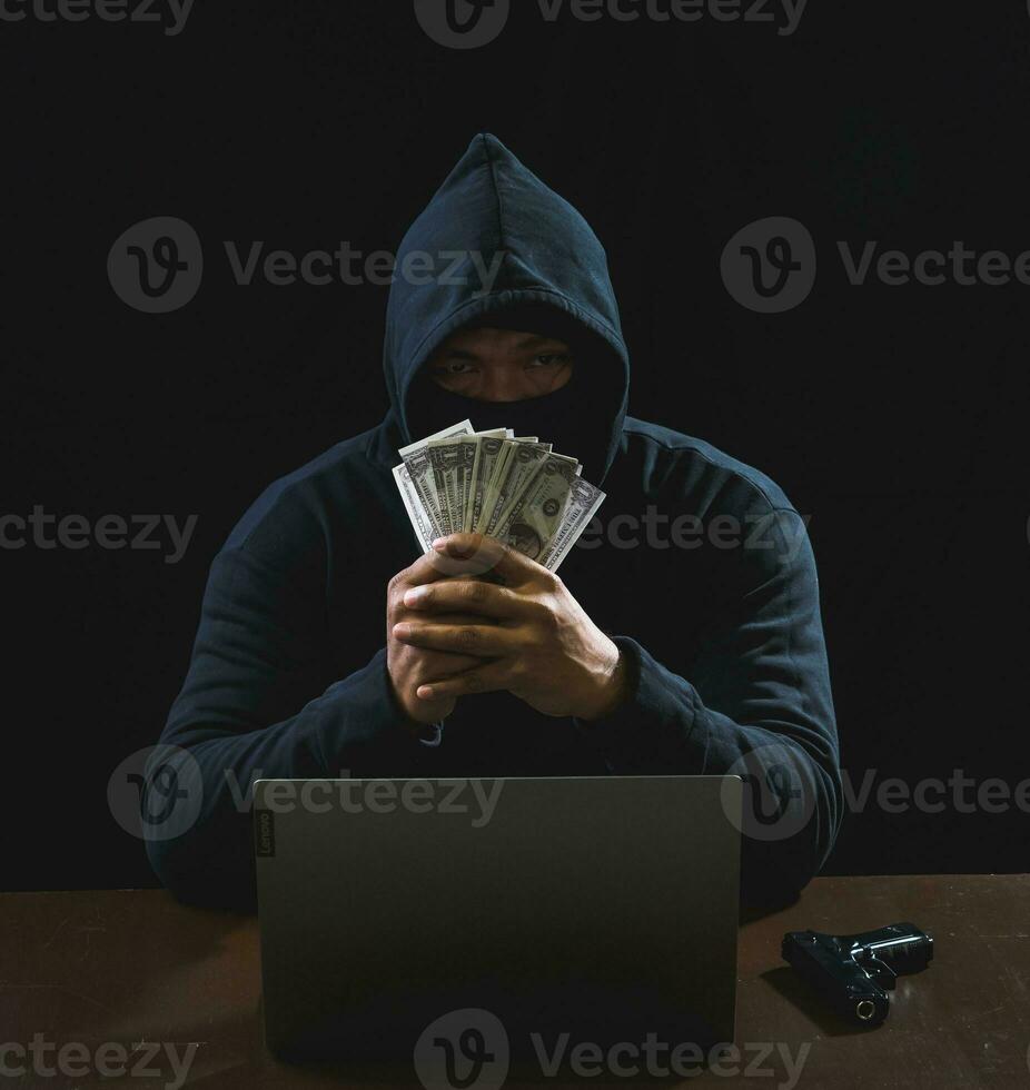 Hacker spy man one person in black hoodie sitting on a table looking computer laptop used login password attack security to circulate data digital in internet network system, night dark background. photo