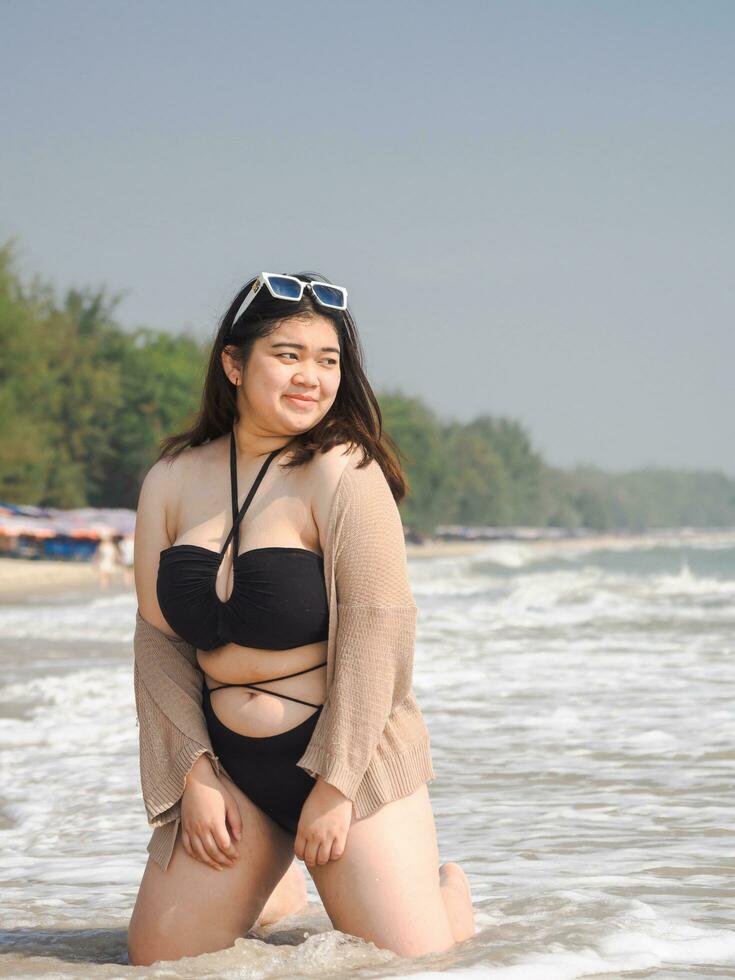 Portrait young woman asian chubby fat cute beautiful one person in bikini black sexy frontview tropical sea beach white sand clean and blue sky background calm nature ocean wave water travel fun happy photo