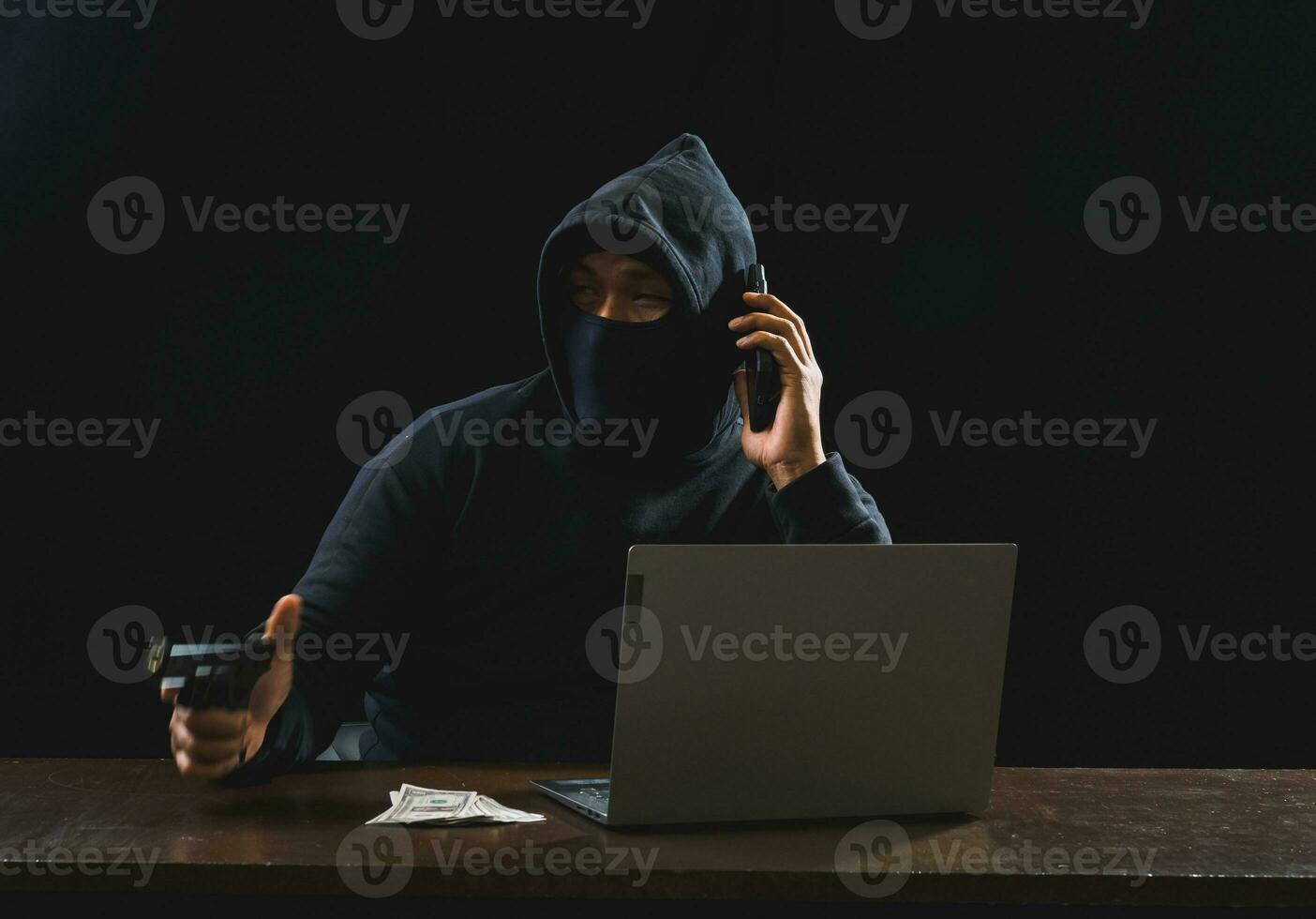 Hacker spy man one person in black hoodie sitting on a table looking computer laptop used login password attack security to circulate data digital in internet network system, night dark background. photo