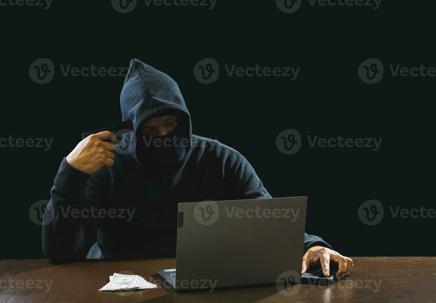 Portrait hacker spy man one person in black hoodie sitting on table looking computer laptop used login password attack security to data digital internet network system night dark background copy space photo