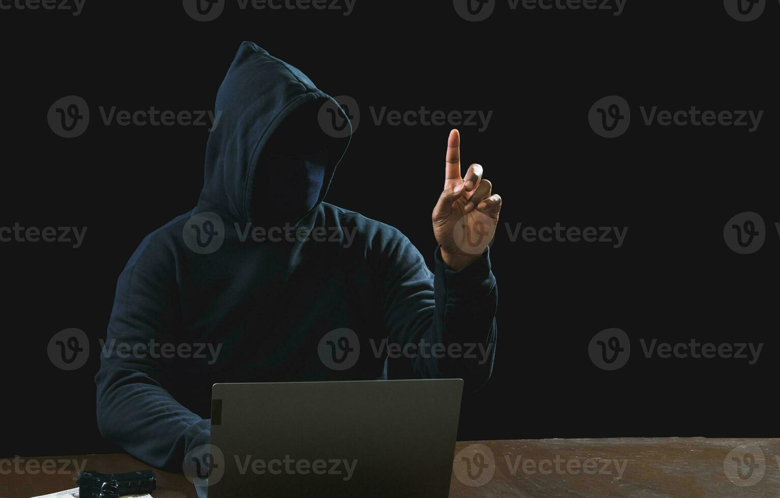 Portrait hacker spy man one person in black hoodie sitting on table looking computer laptop used login password attack security to data digital internet network system night dark background copy space photo