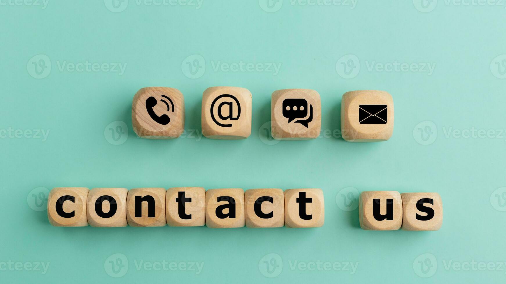 Contact us text on wooden cubes on a blue background. Wooden cube symbol telephone, mail, address, and mobile phone. Website page contact us or e-mail marketing concept. photo