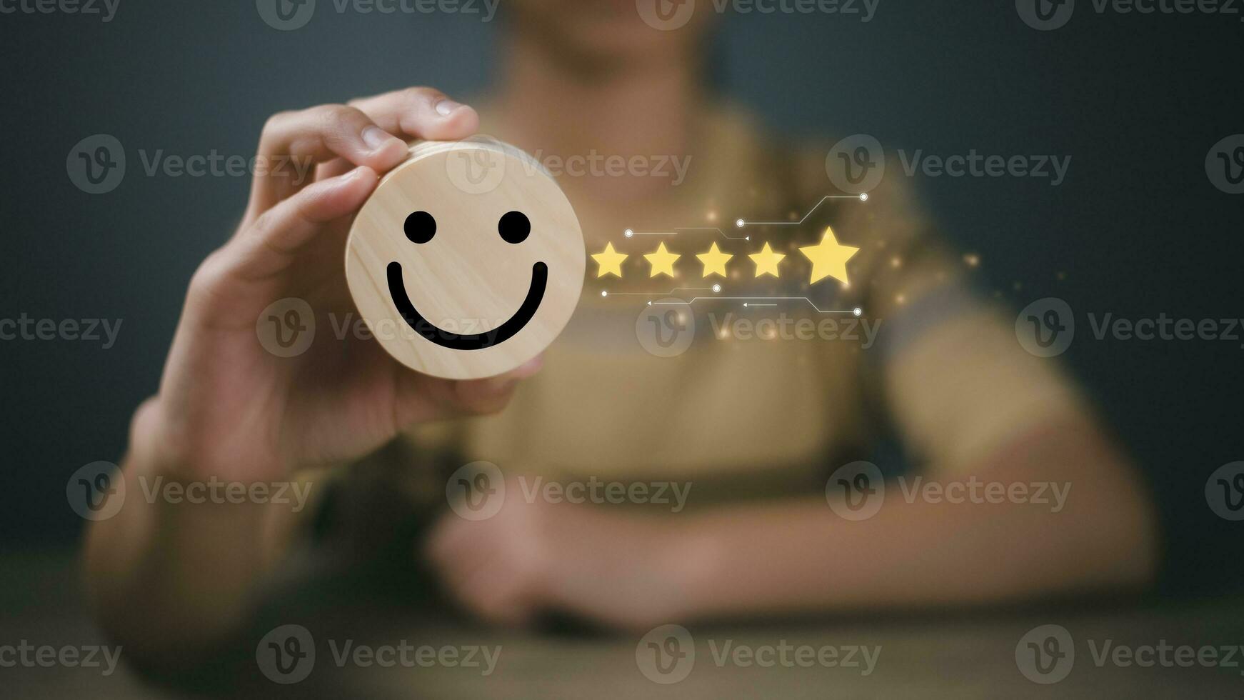 Customer review, customer service evaluation, and satisfaction concept. A businesswoman selects the smiley icon and gives five stars on a wooden block. photo
