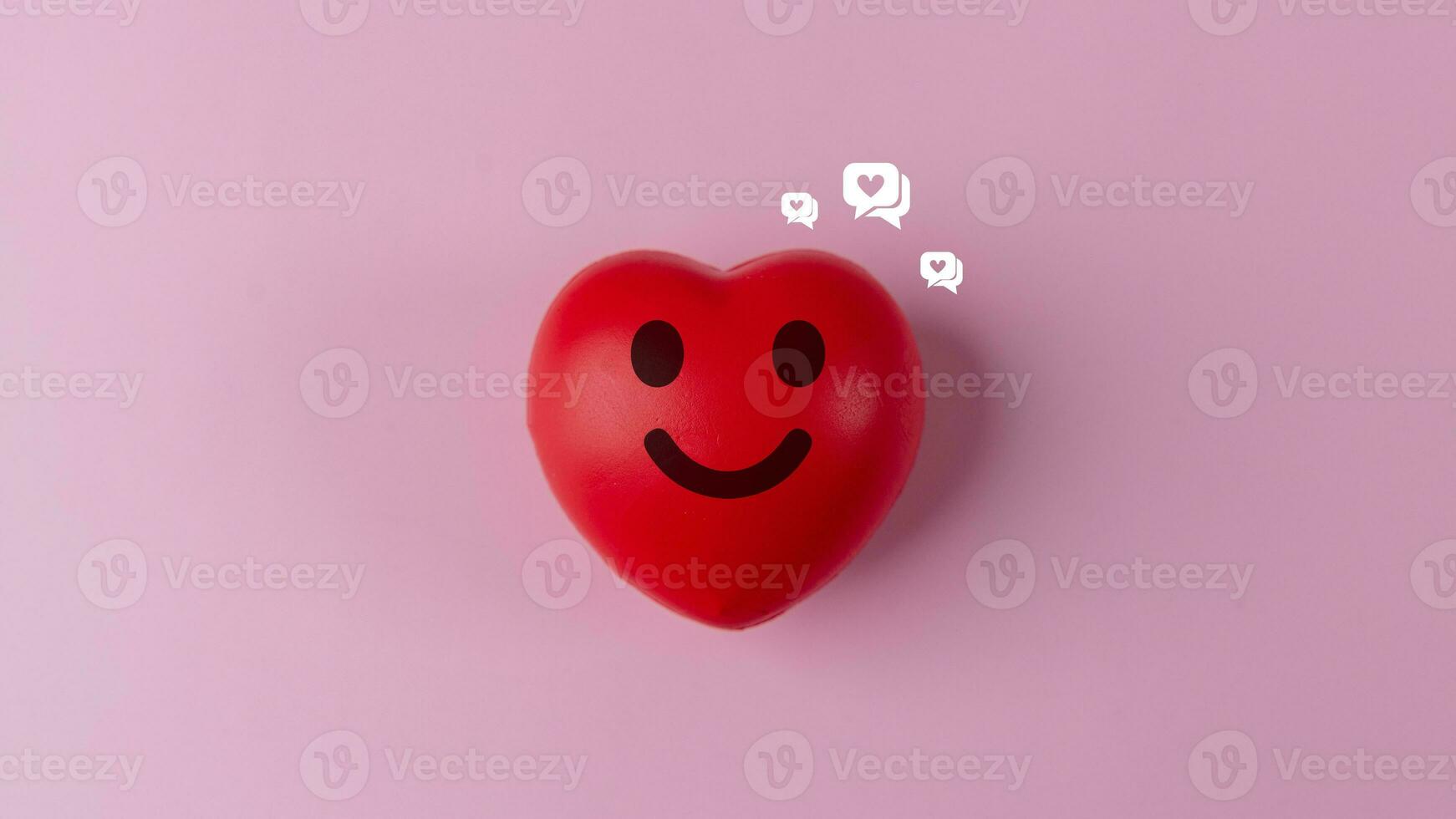 Red heart with smiley face and social media icons on pink background photo