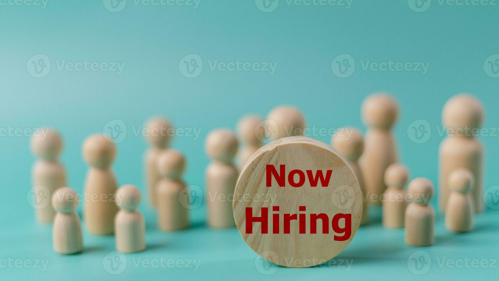 The concept is now hiring. Wooden figures of people and the word NOW HIRING. Business concept photo