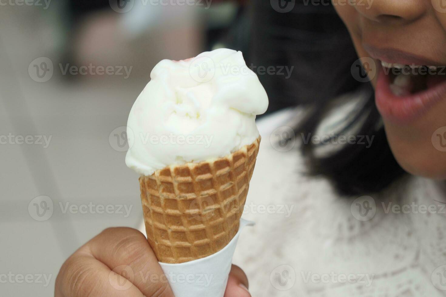 niño mano participación vainilla hielo crema en un gofre cono. foto