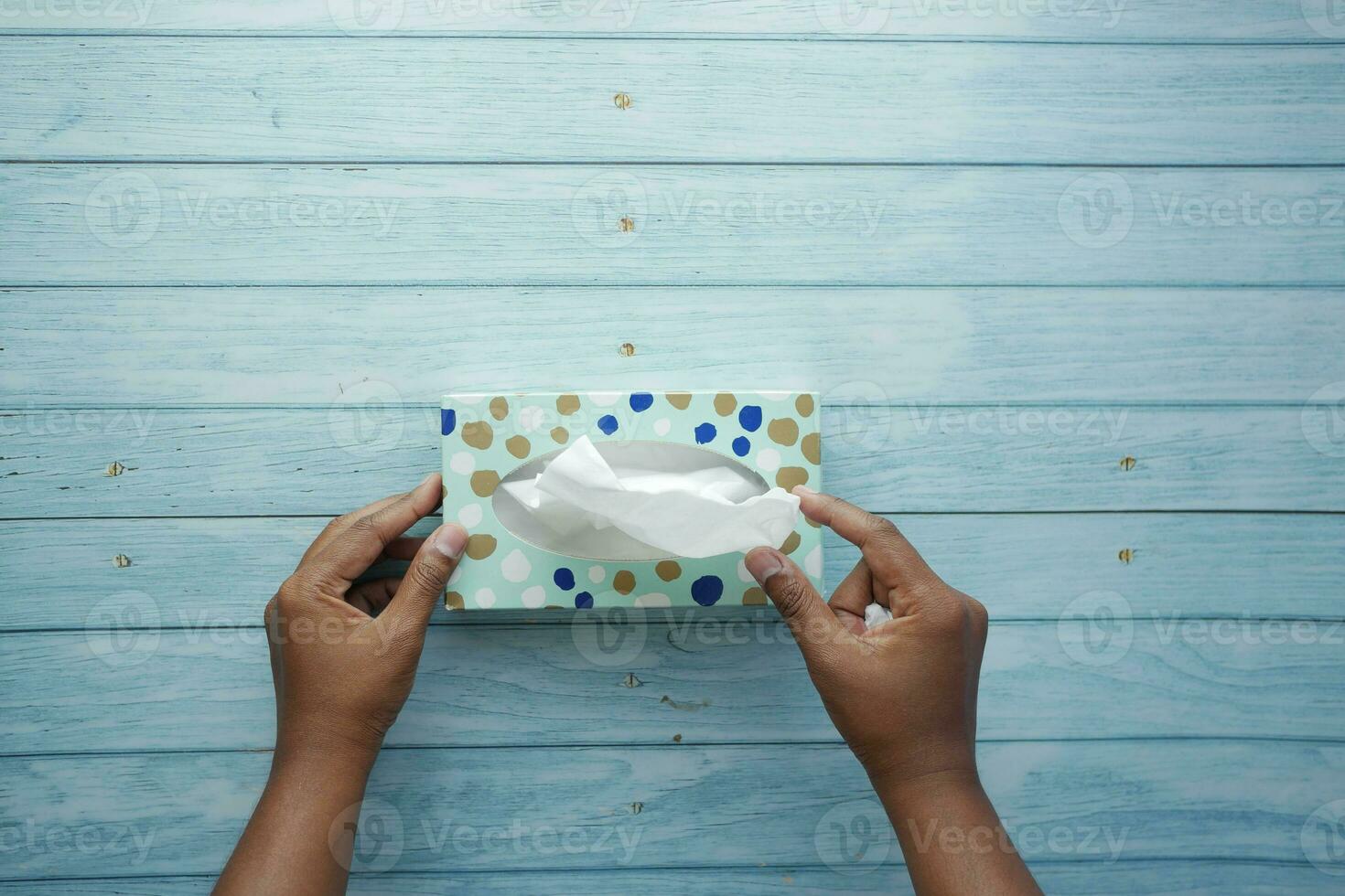 hand pull out a piece of tissue from tissue paper box photo