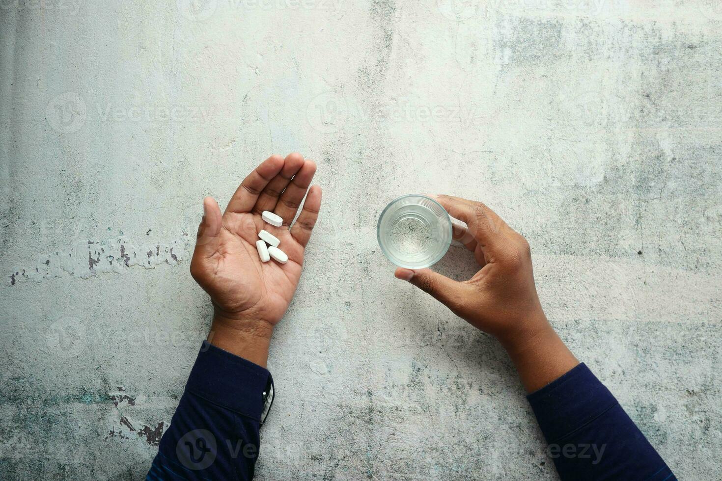 parte superior ver de joven hombres tomando médico píldora y participación un vaso de agua foto