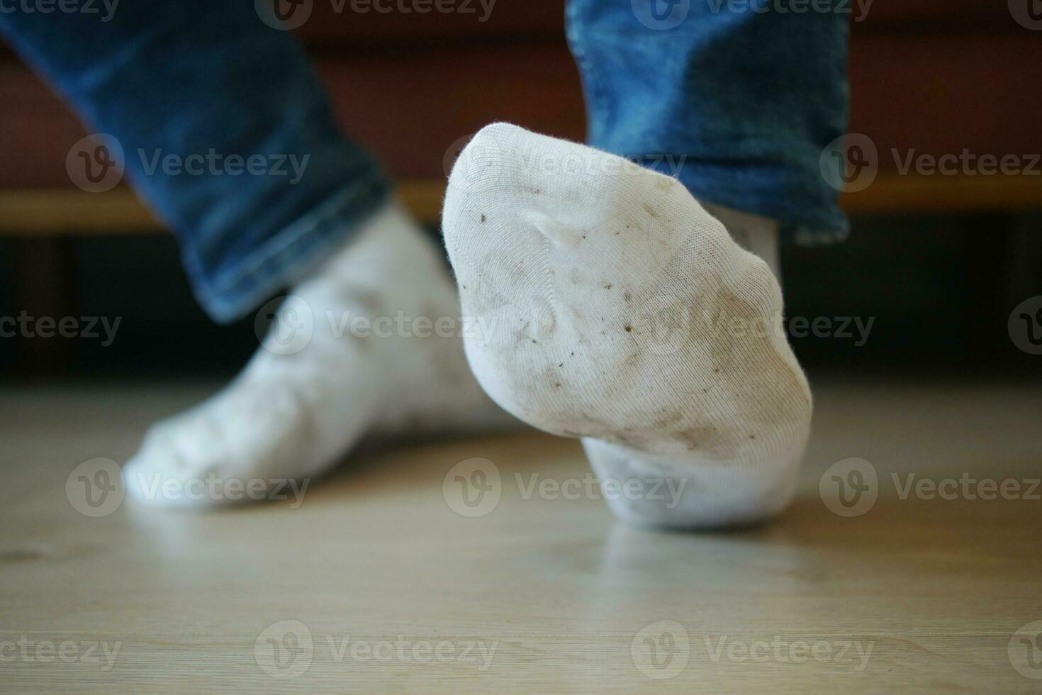 men feet with dirty socks while sitting on sofa photo