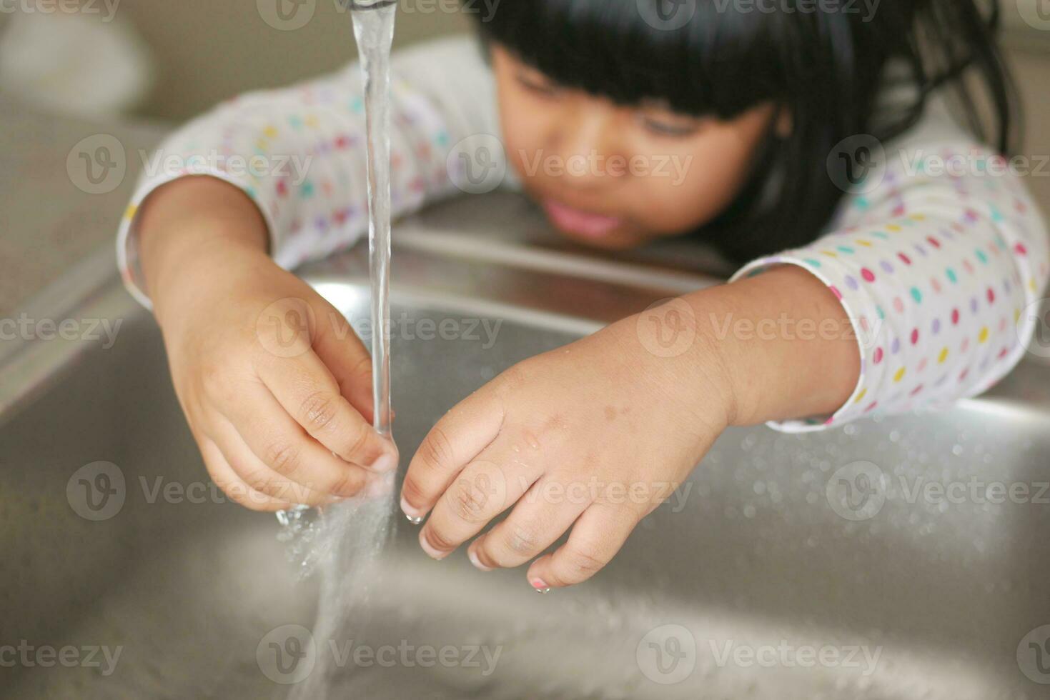 child washing hands with water at kitchen sink photo