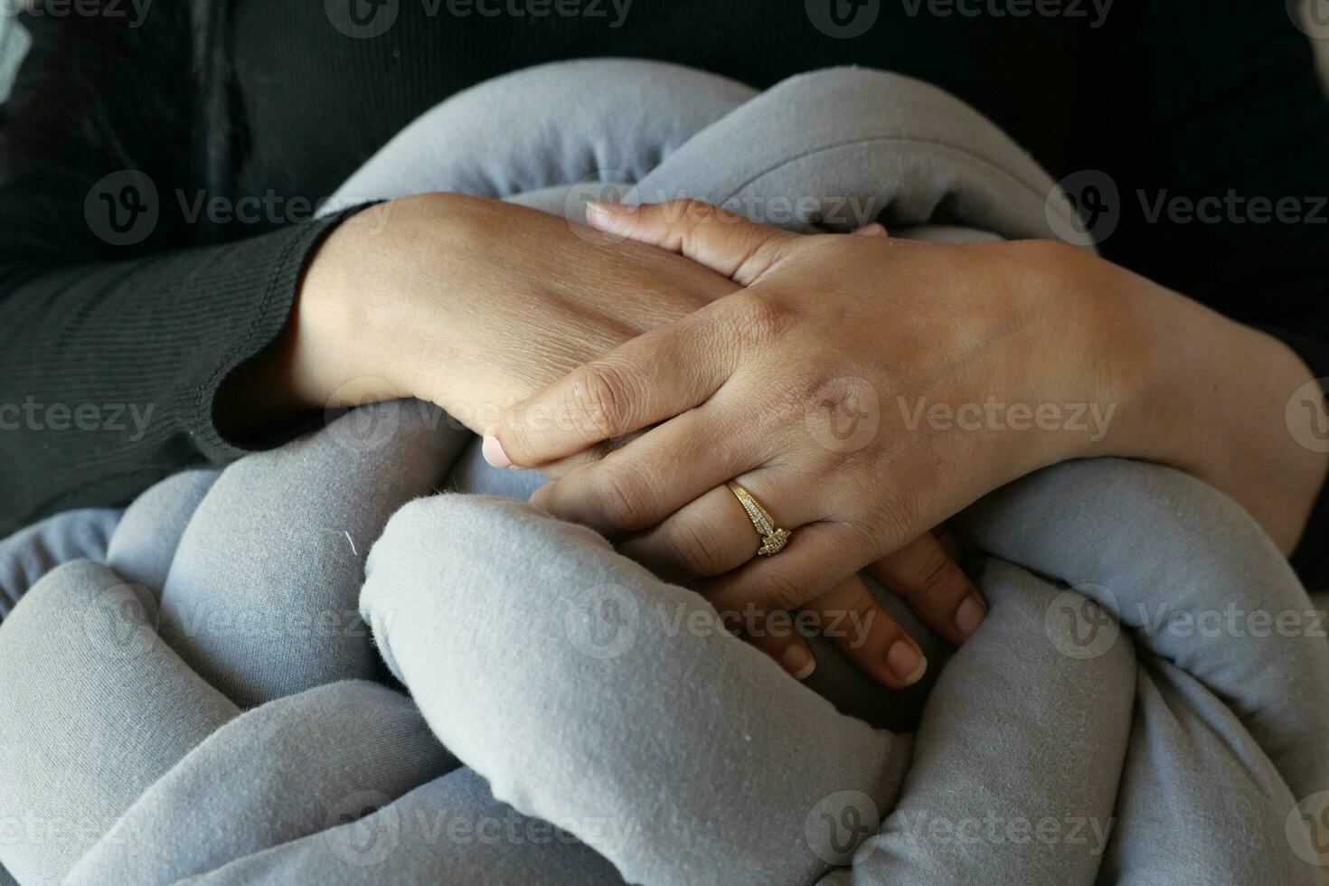 women holding a orange color pillow while sit on a sofa , photo