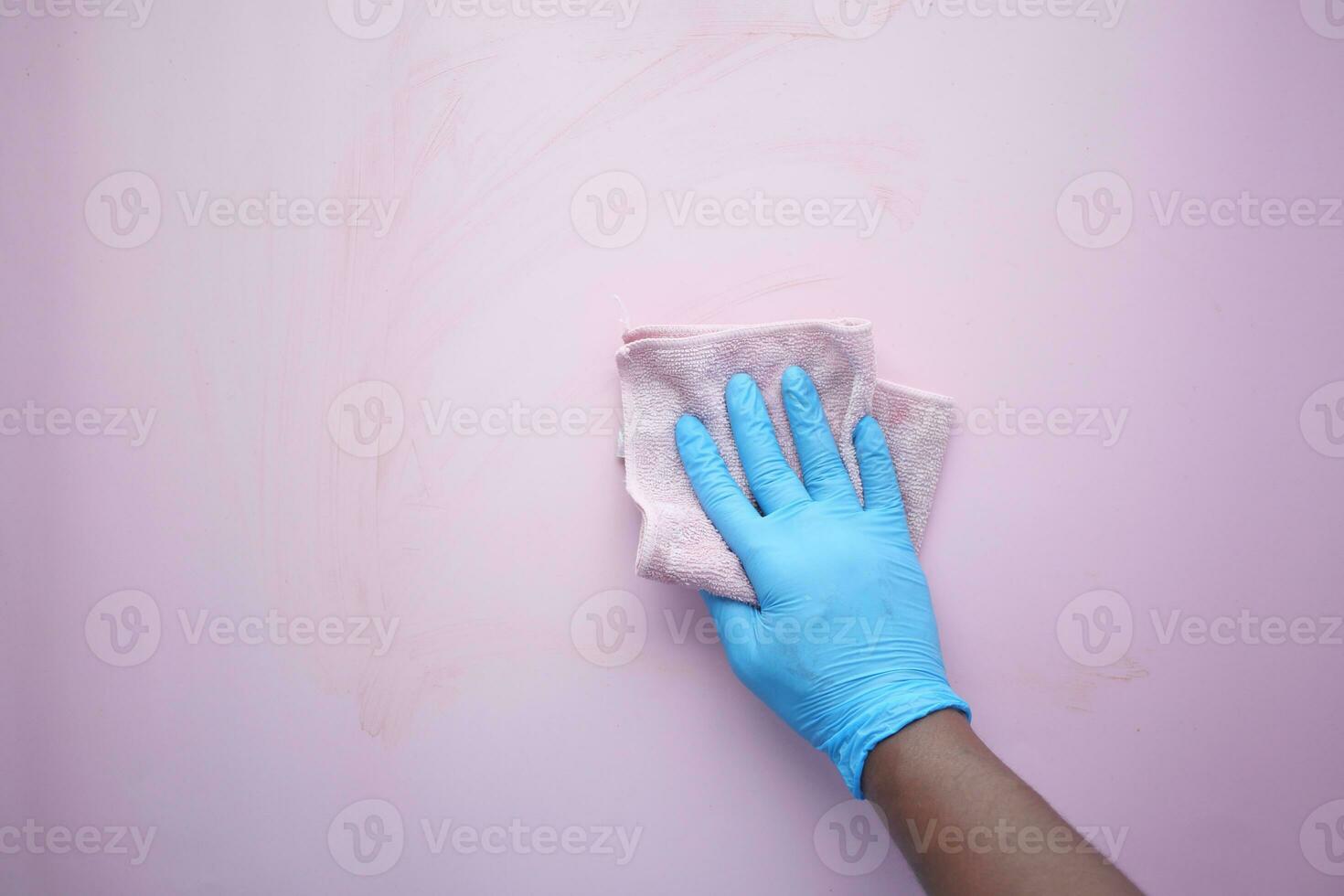 hand in blue rubber gloves cleaning table with cloth photo