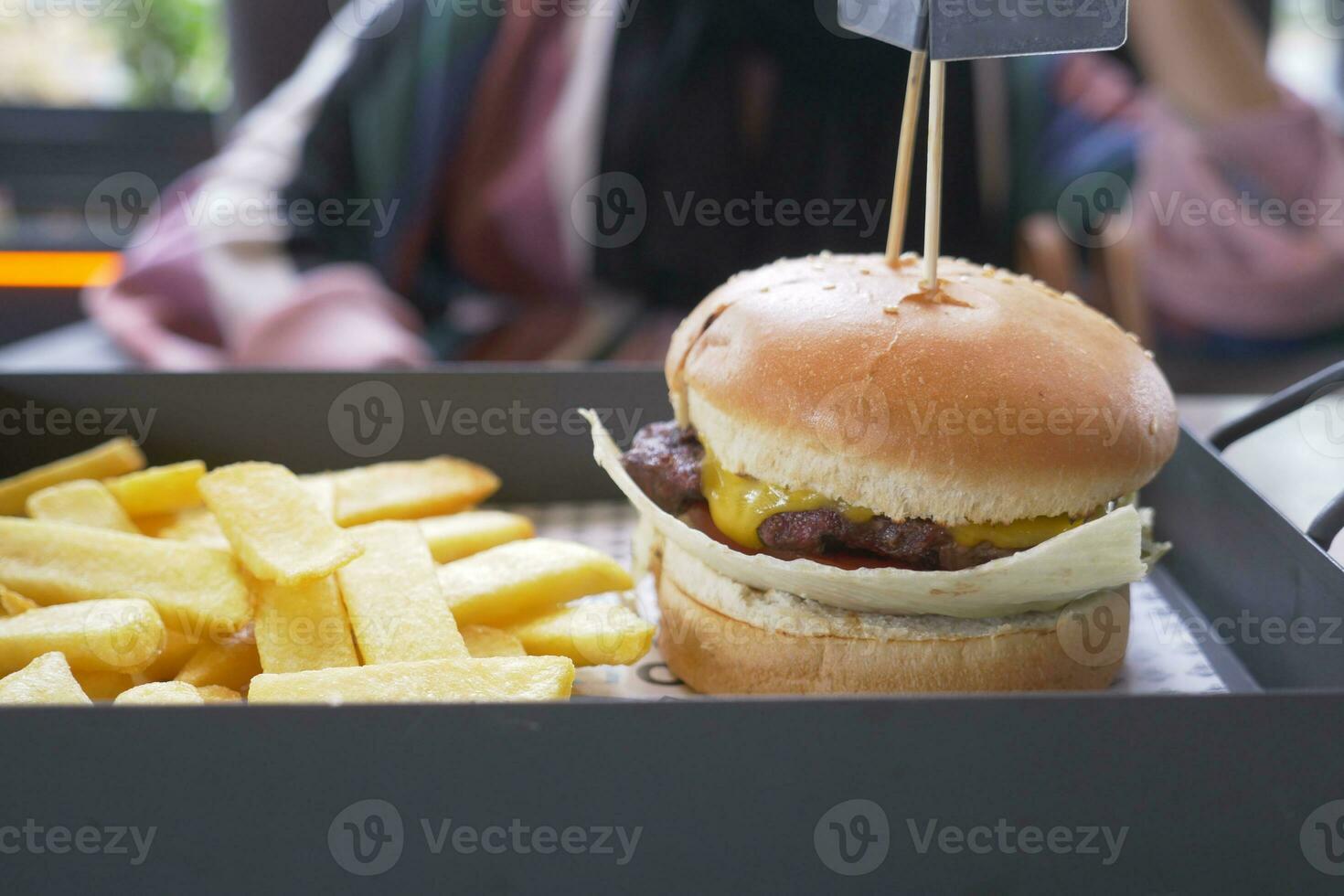 hand holding beef burger on table close up photo