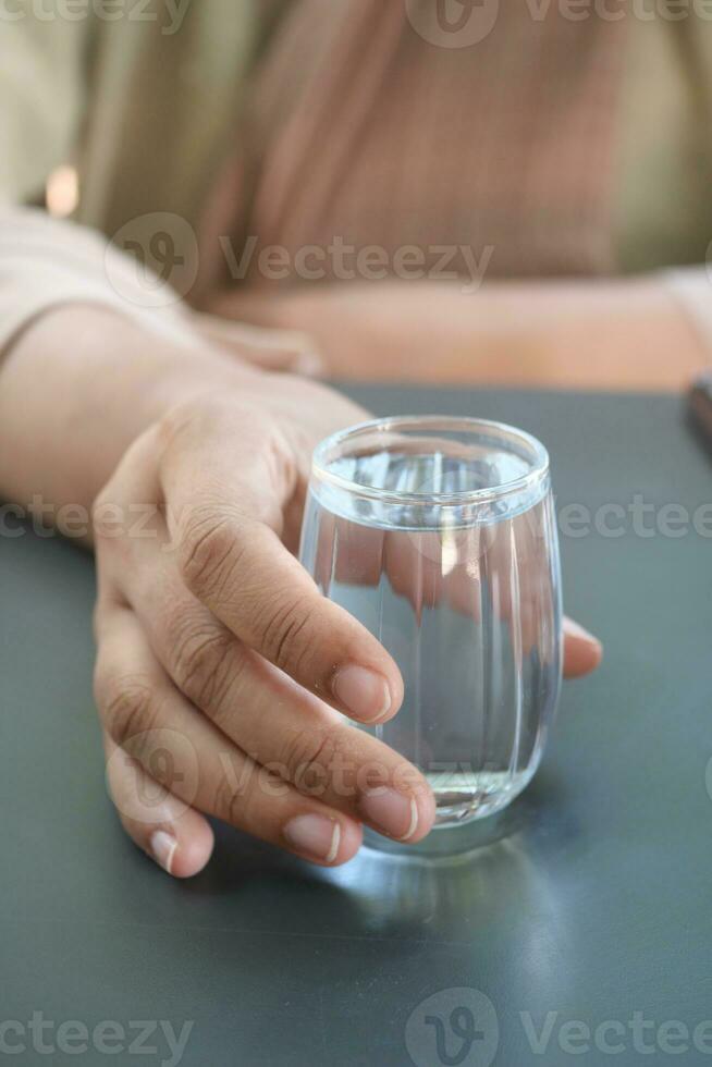 mujer participación un vaso de agua en mesa foto