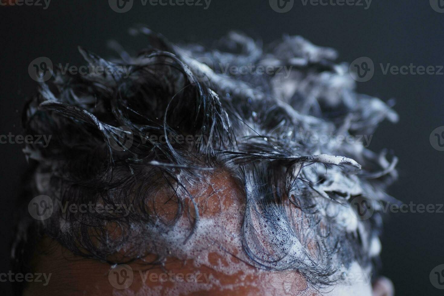 young men washes h his hair with shampoo . photo