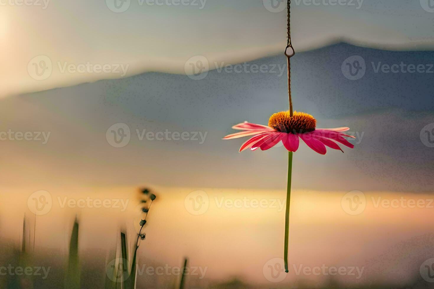 a pink flower hanging from a string in front of a mountain. AI-Generated photo