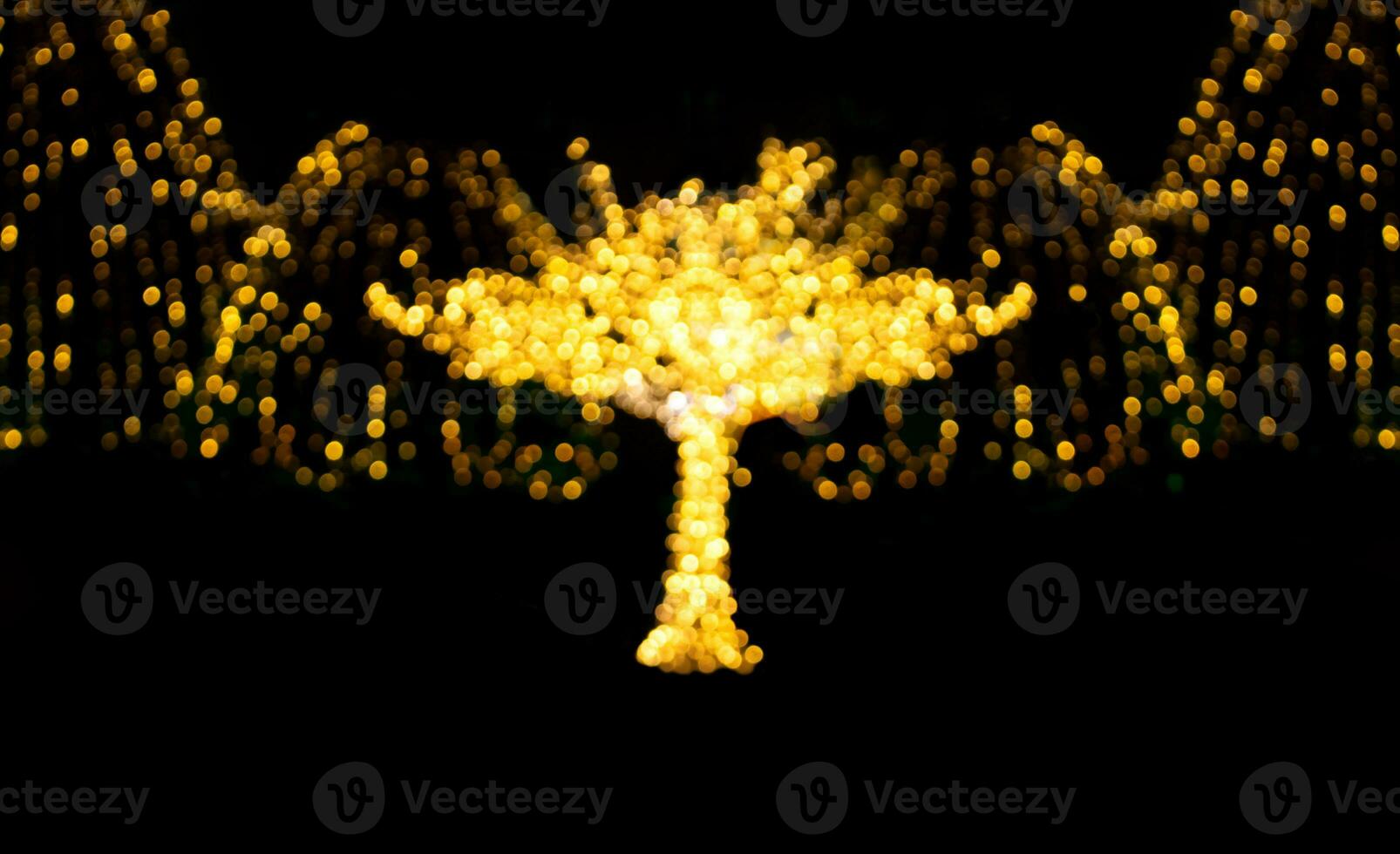 Defocused illuminated tree with blurred lights with garlands on black isolated background. City, holiday lighting. Christmas, New Year, holidays, evening lanterns. Soft focus. Copy space photo