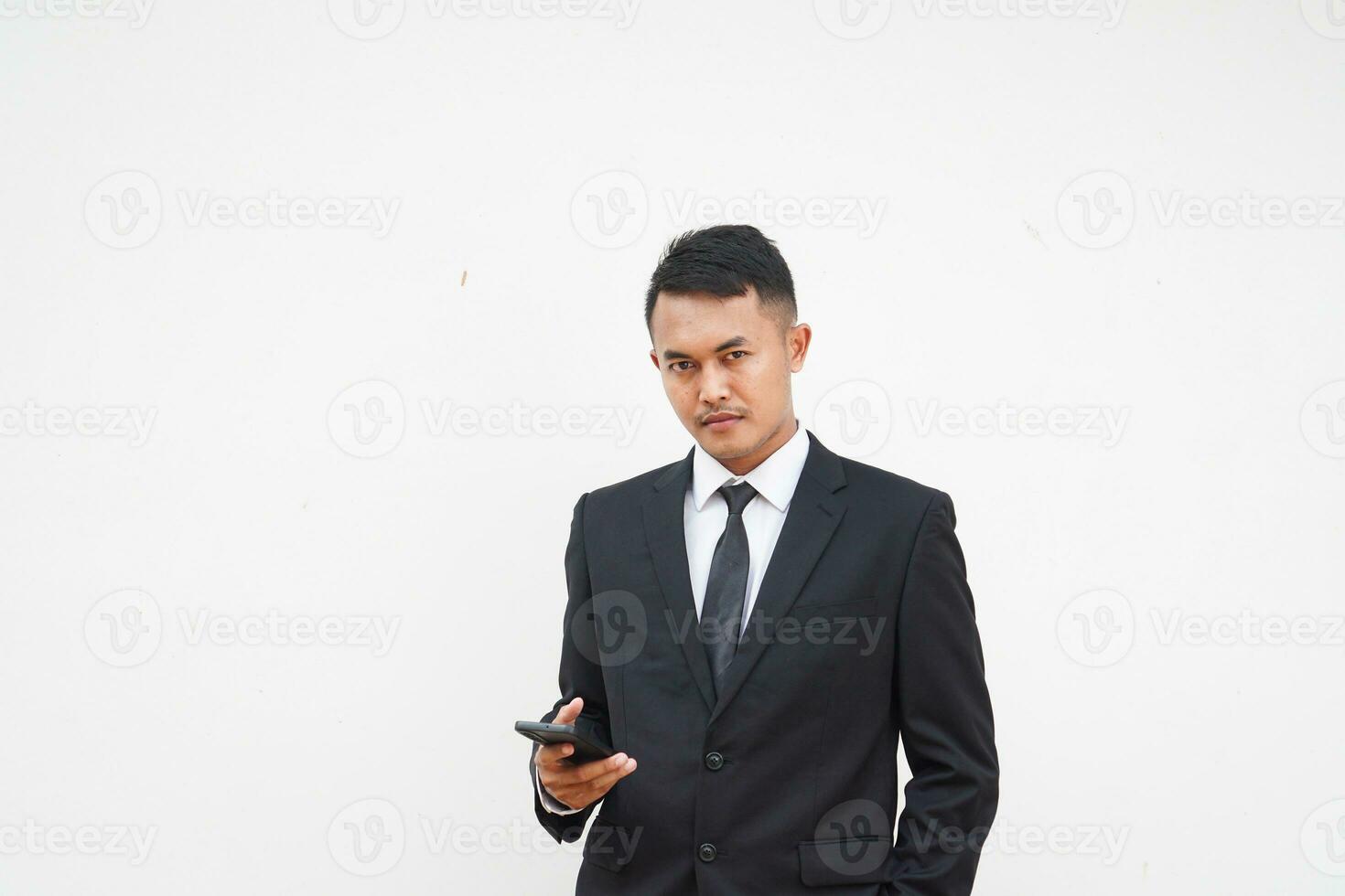 Handsome Asian young businessman using mobile phone with black suit on white background photo