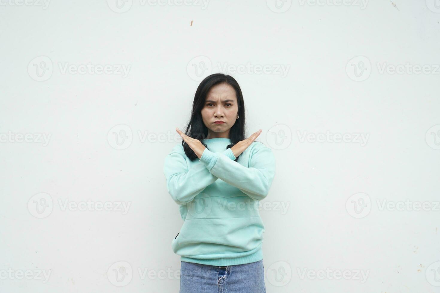 Portrait Indonesian beautiful woman wearing light blue sweater with stop and reject gesture with cross x hand isolated on white background photo