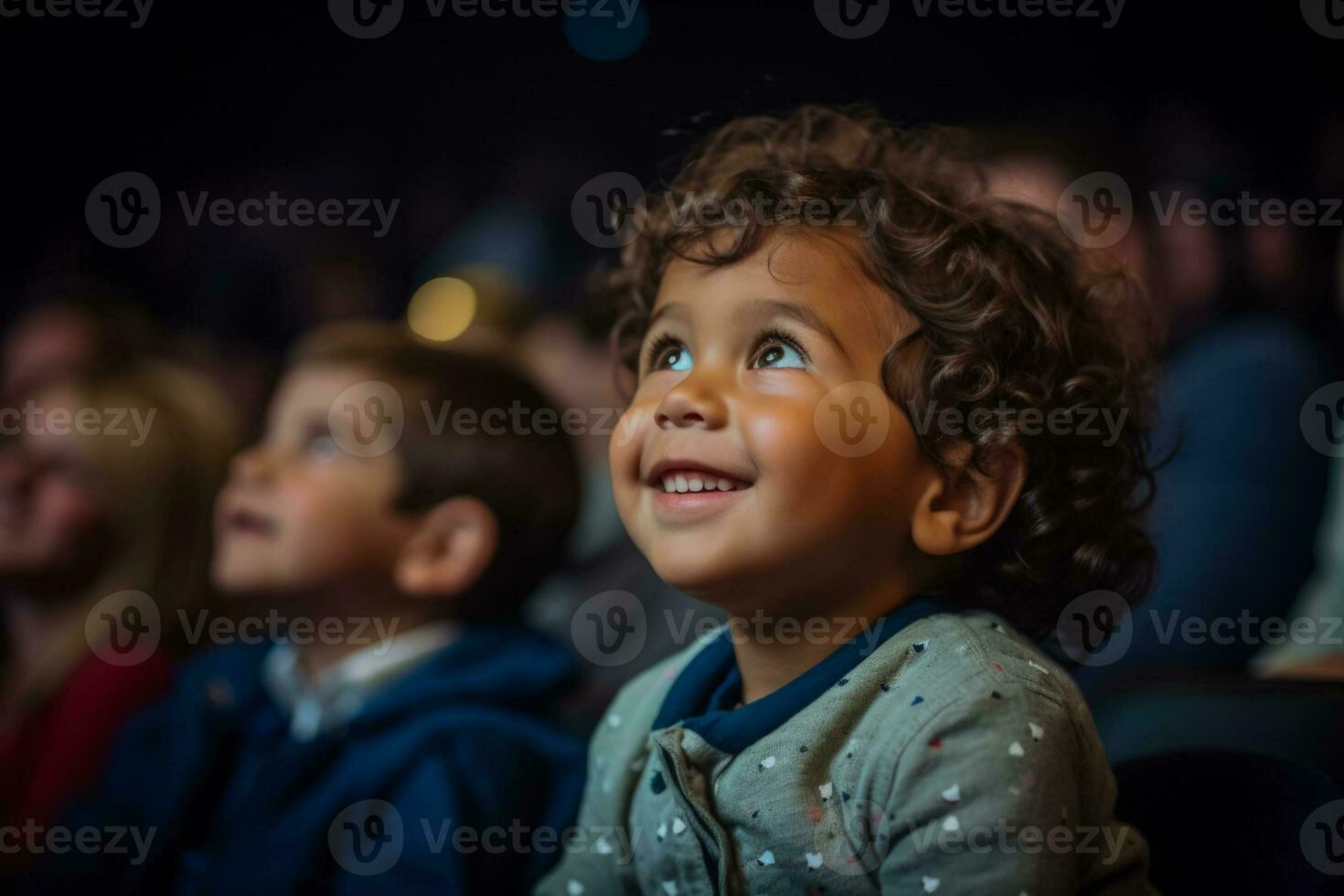A wide eyed little boy gazes with wonder at the stage during his first theater visit photo