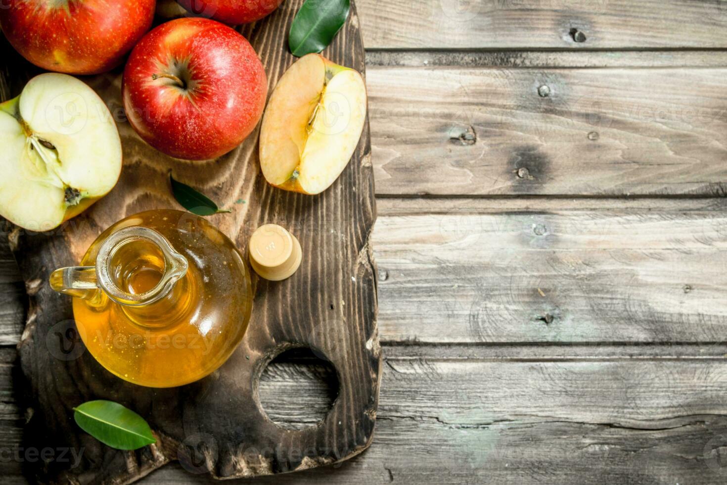 Apple cider vinegar with fresh red apples on a cutting Board. photo