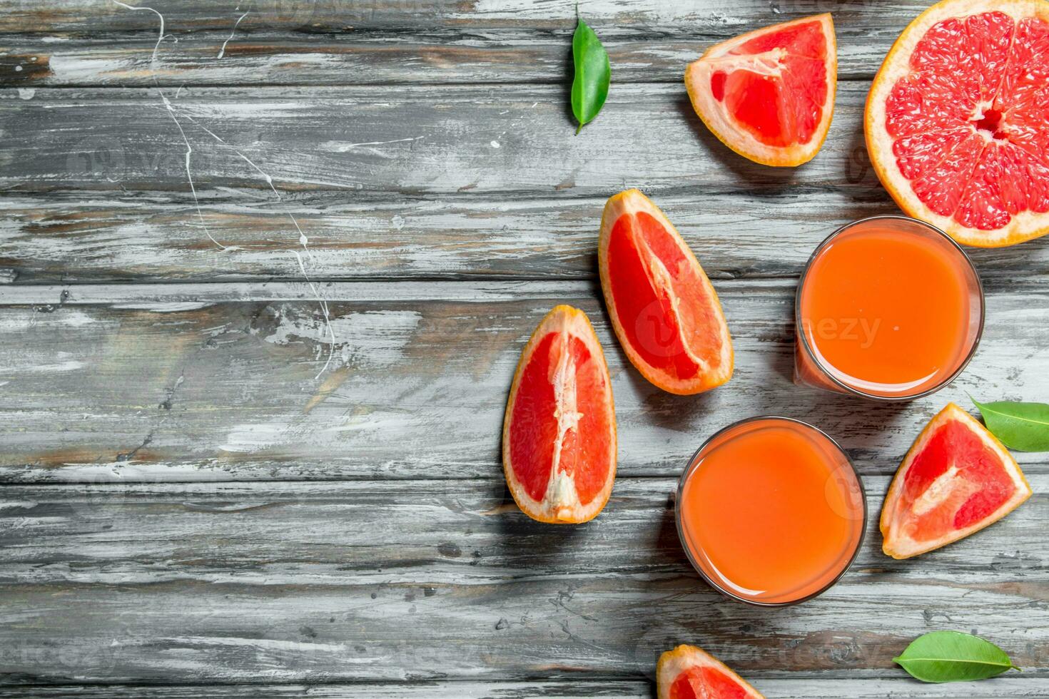 Grapefruit juice in a glass and pieces of fresh grapefruit. photo