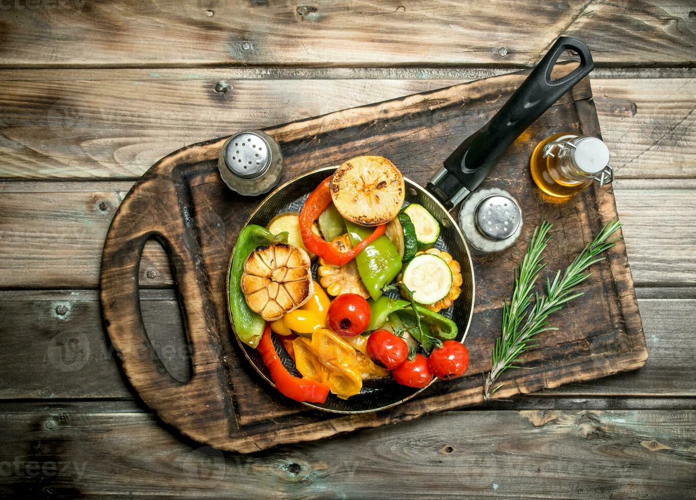 Assortment of grilled vegetables with a pan of herbs and spices on a cutting Board. photo
