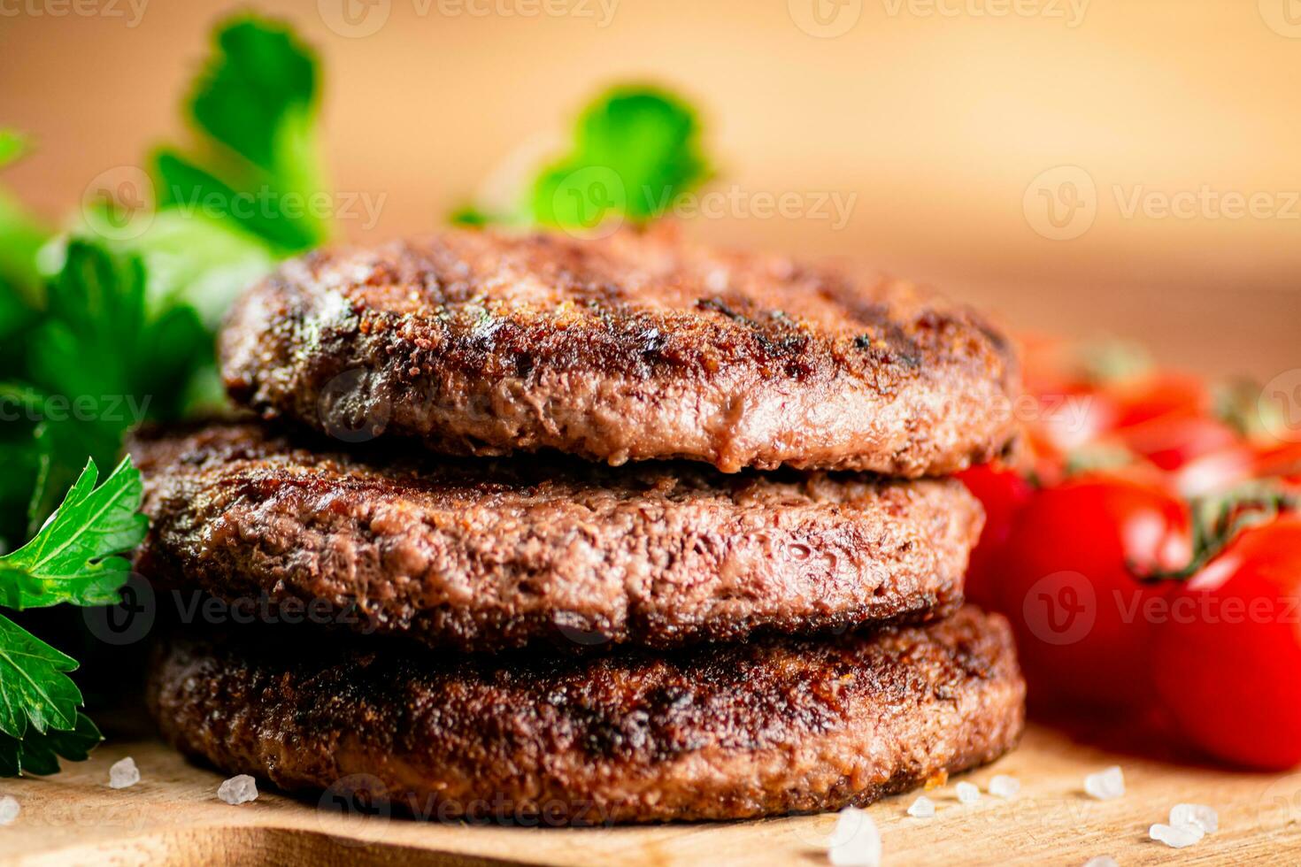 Burger grill on a cutting board with greens and tomatoes. photo