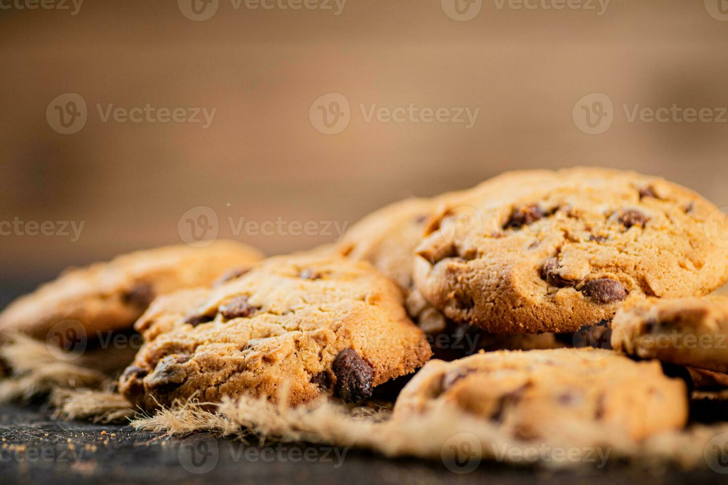 Pile of homemade cookies with pieces of milk chocolate on the table. photo