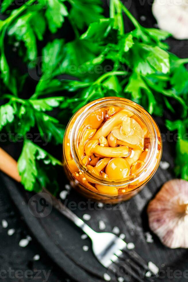 Marinated mushrooms with a glass jar with parsley and garlic. photo