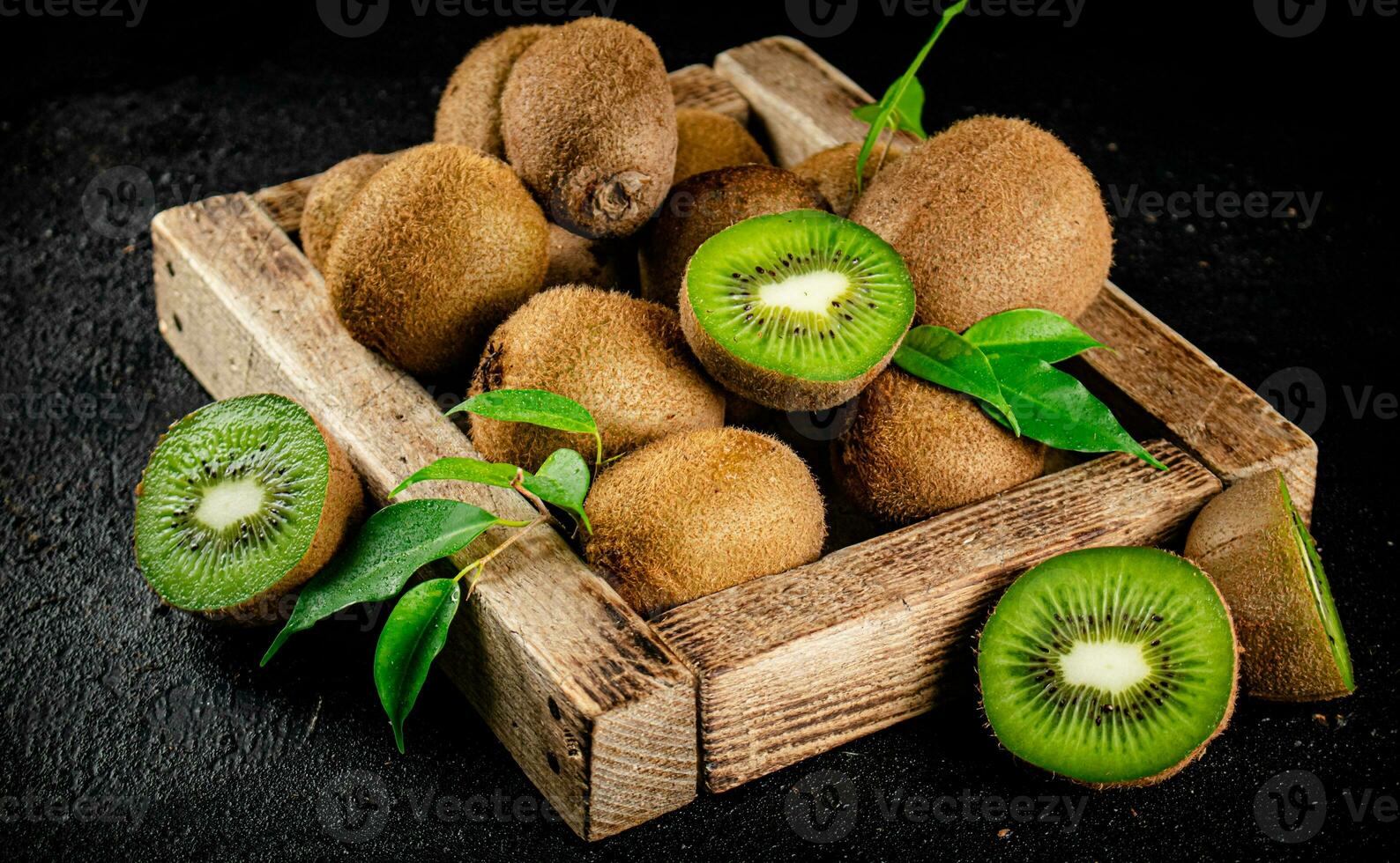 Ripe kiwi with leaves on a wooden tray. photo
