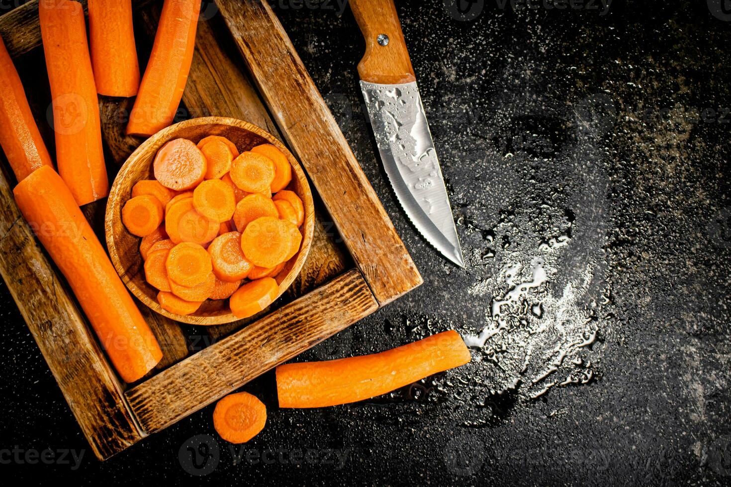 Whole and sliced carrots on a wooden tray. photo