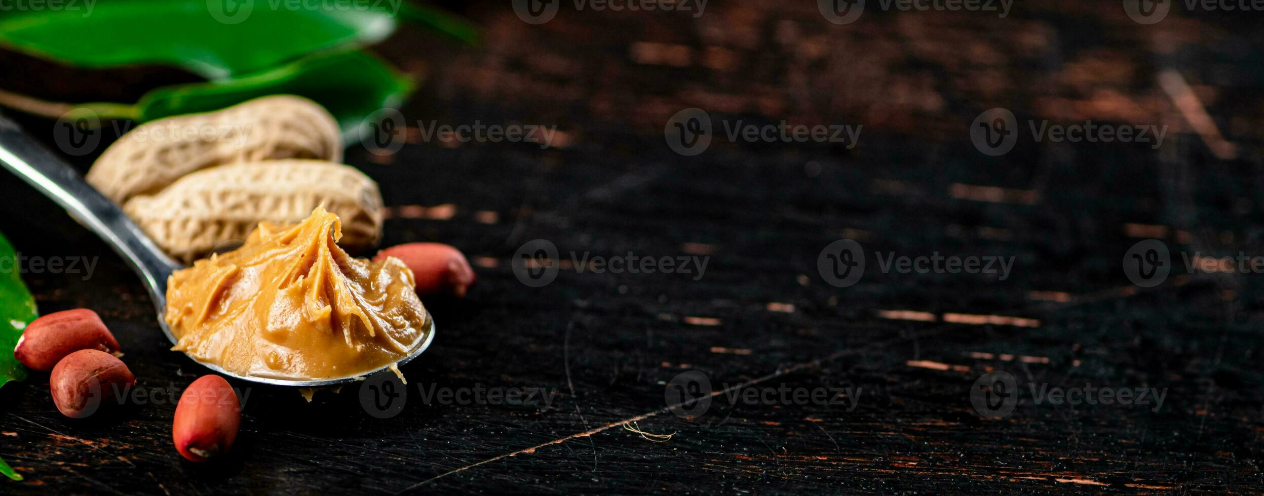 A spoonful of peanut butter on a table with leaves. photo