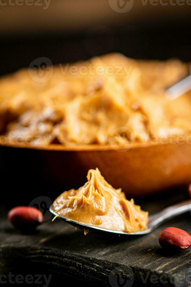 Peanut butter in a spoon on a cutting board. photo