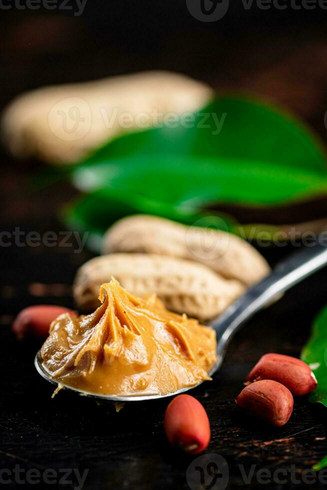 A spoonful of peanut butter on a table with leaves. photo