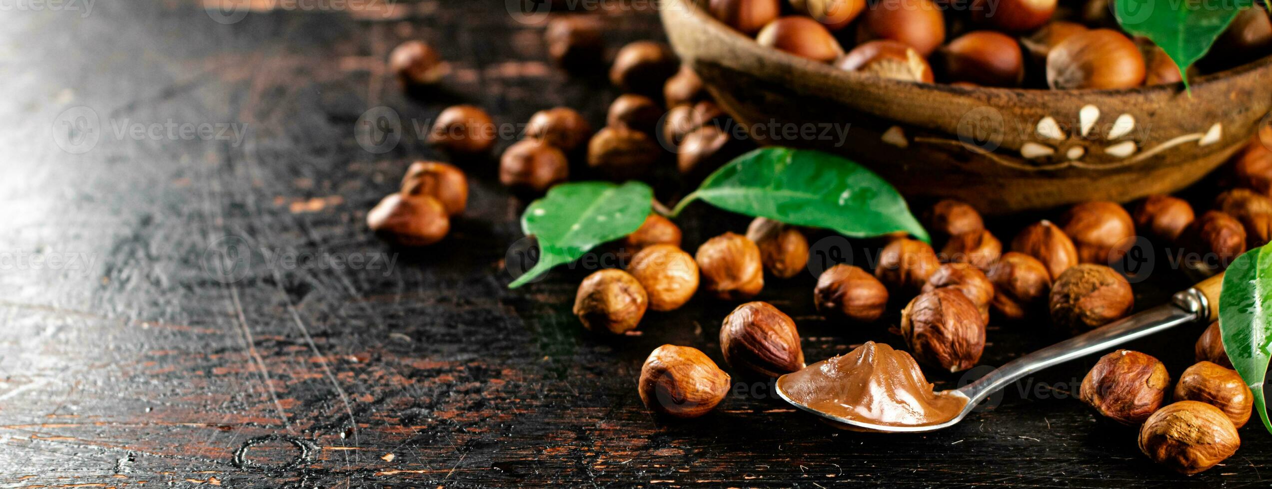 Hazelnut butter in a spoon on a table with leaves. photo