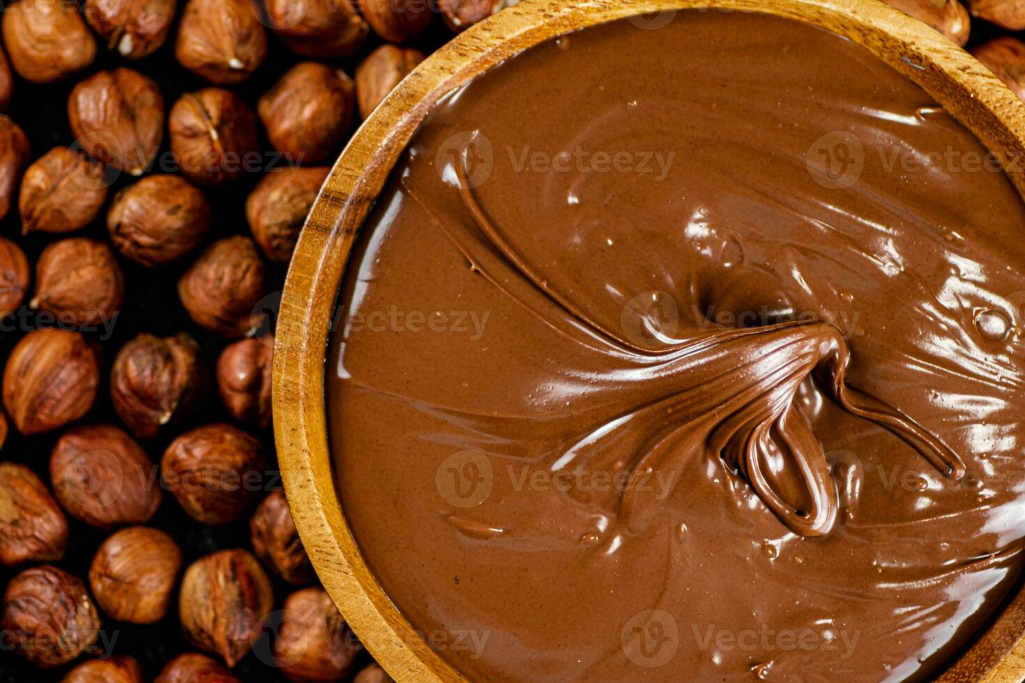 Hazelnut butter on a wooden plate with peeled hazelnuts. photo