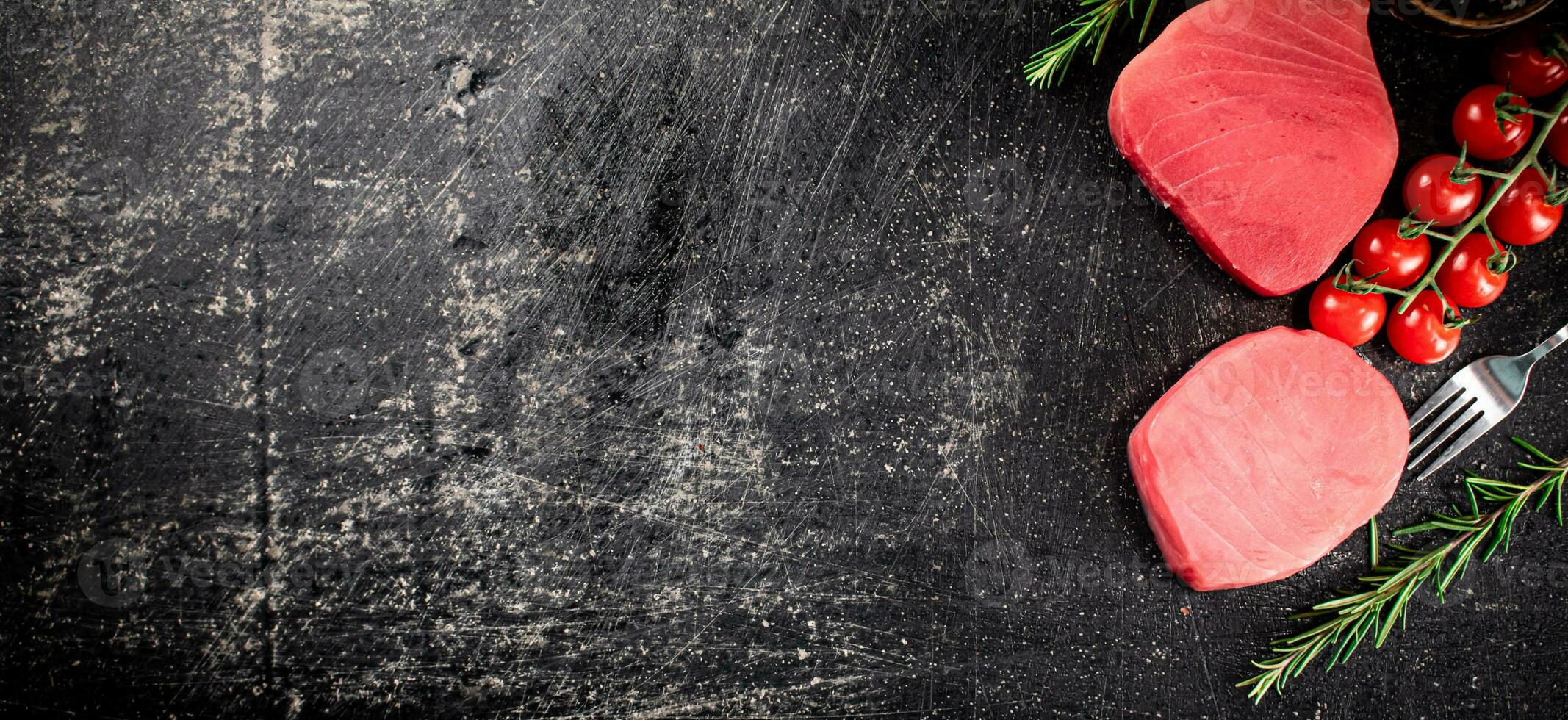 Fresh raw tuna steak with tomatoes and rosemary. photo