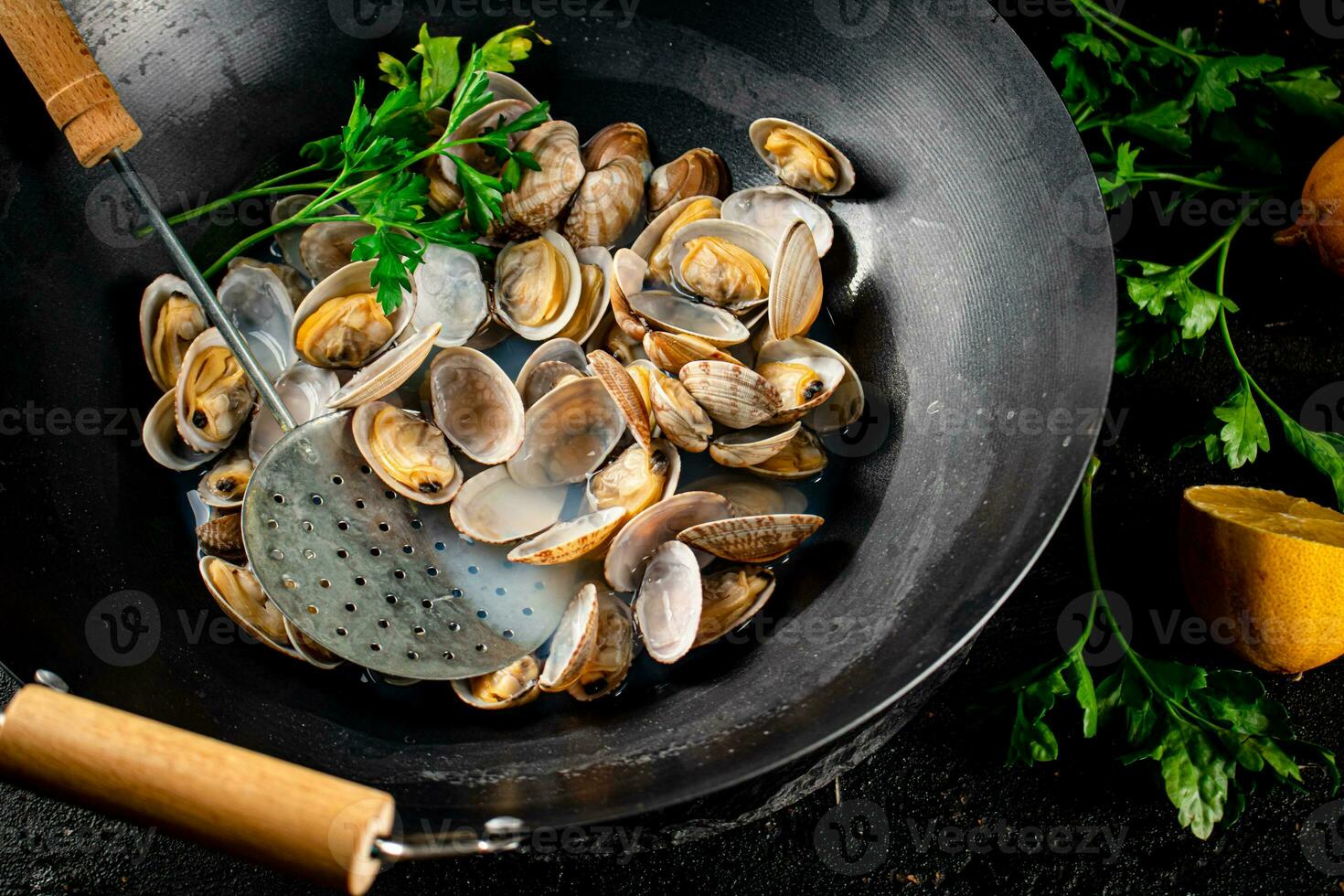 Vongole in a saucepan with lemon slices and parsley. photo
