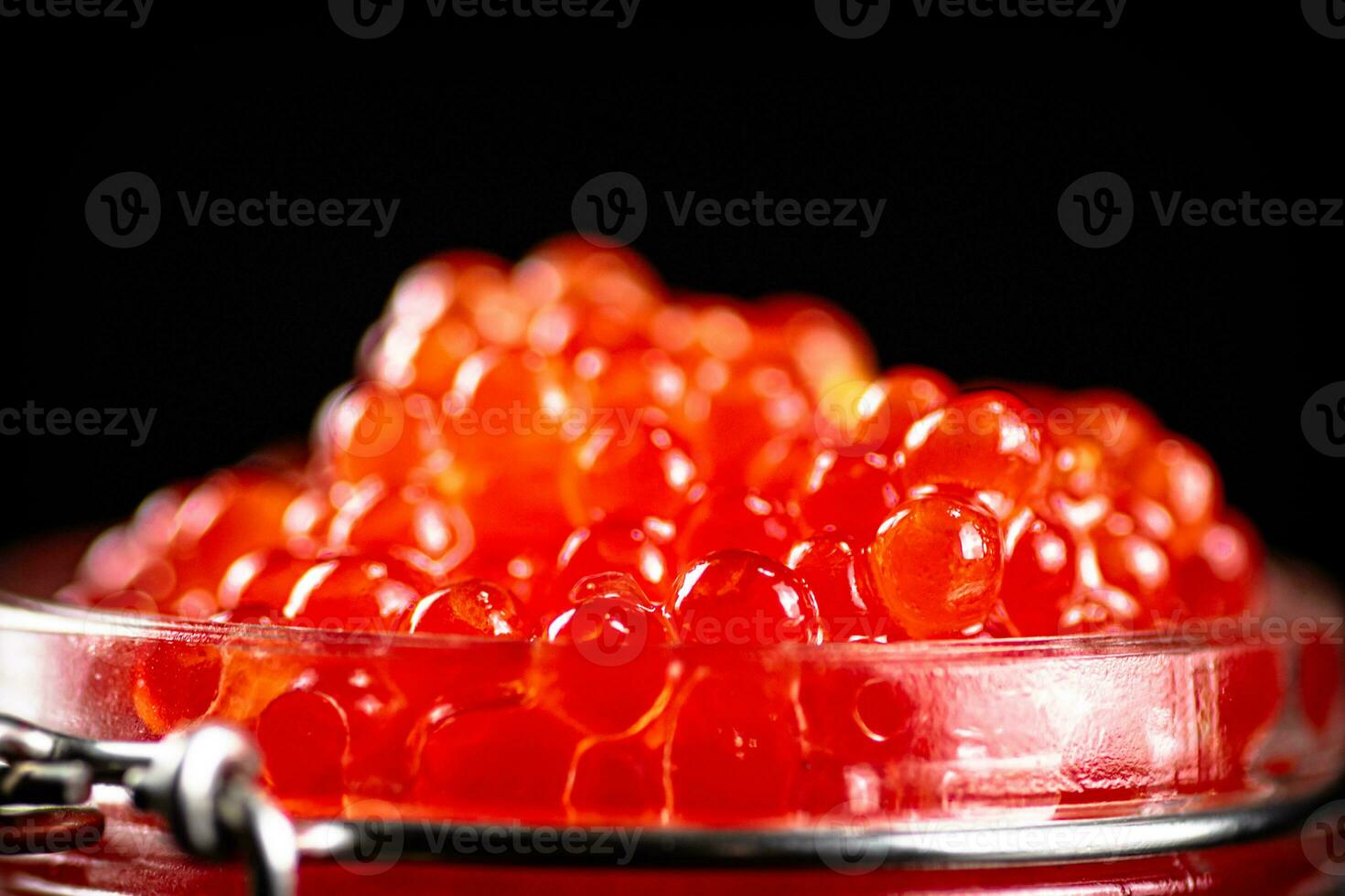 Grains of red caviar on a black background. photo