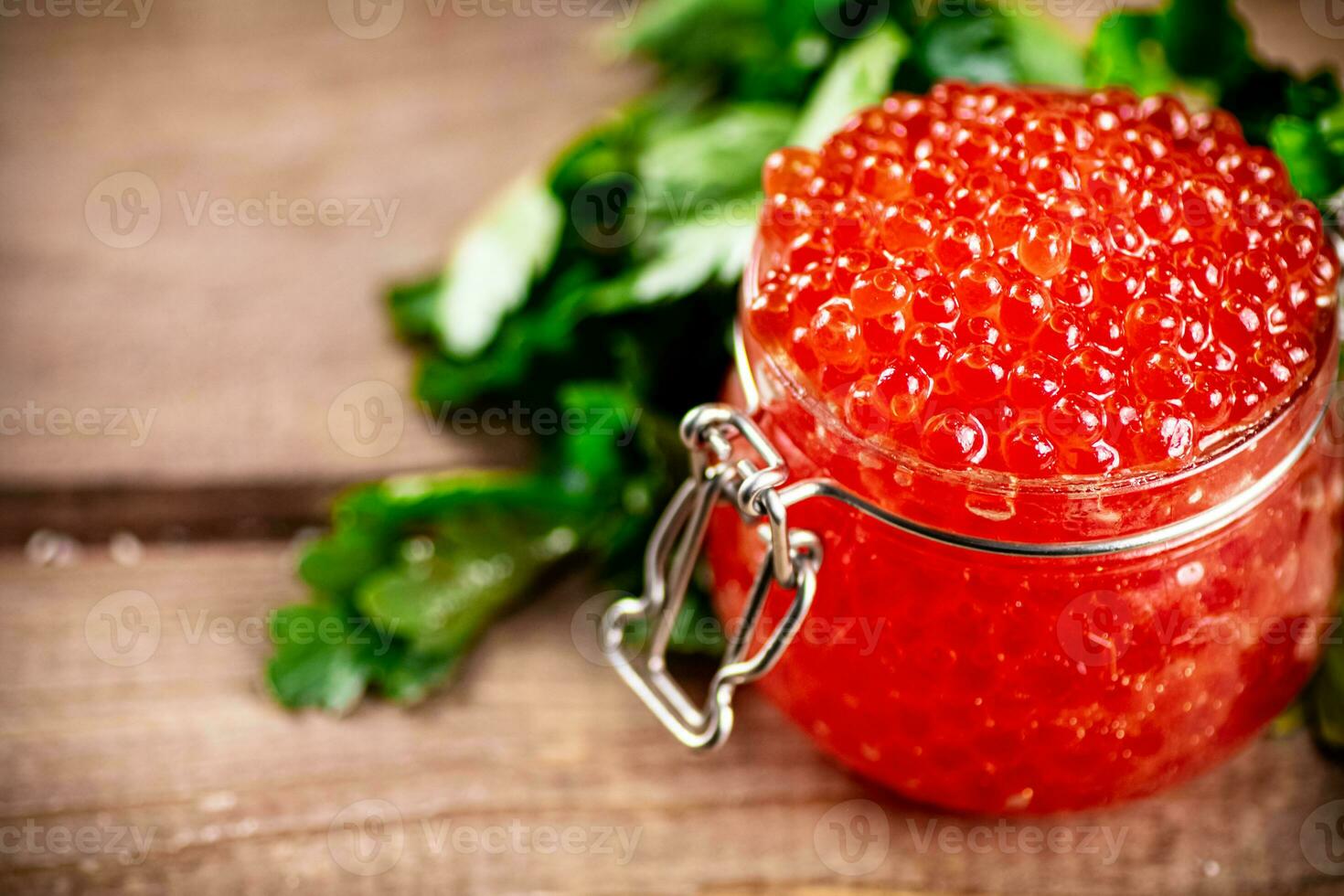 Red caviar in a glass jar with parsley. photo