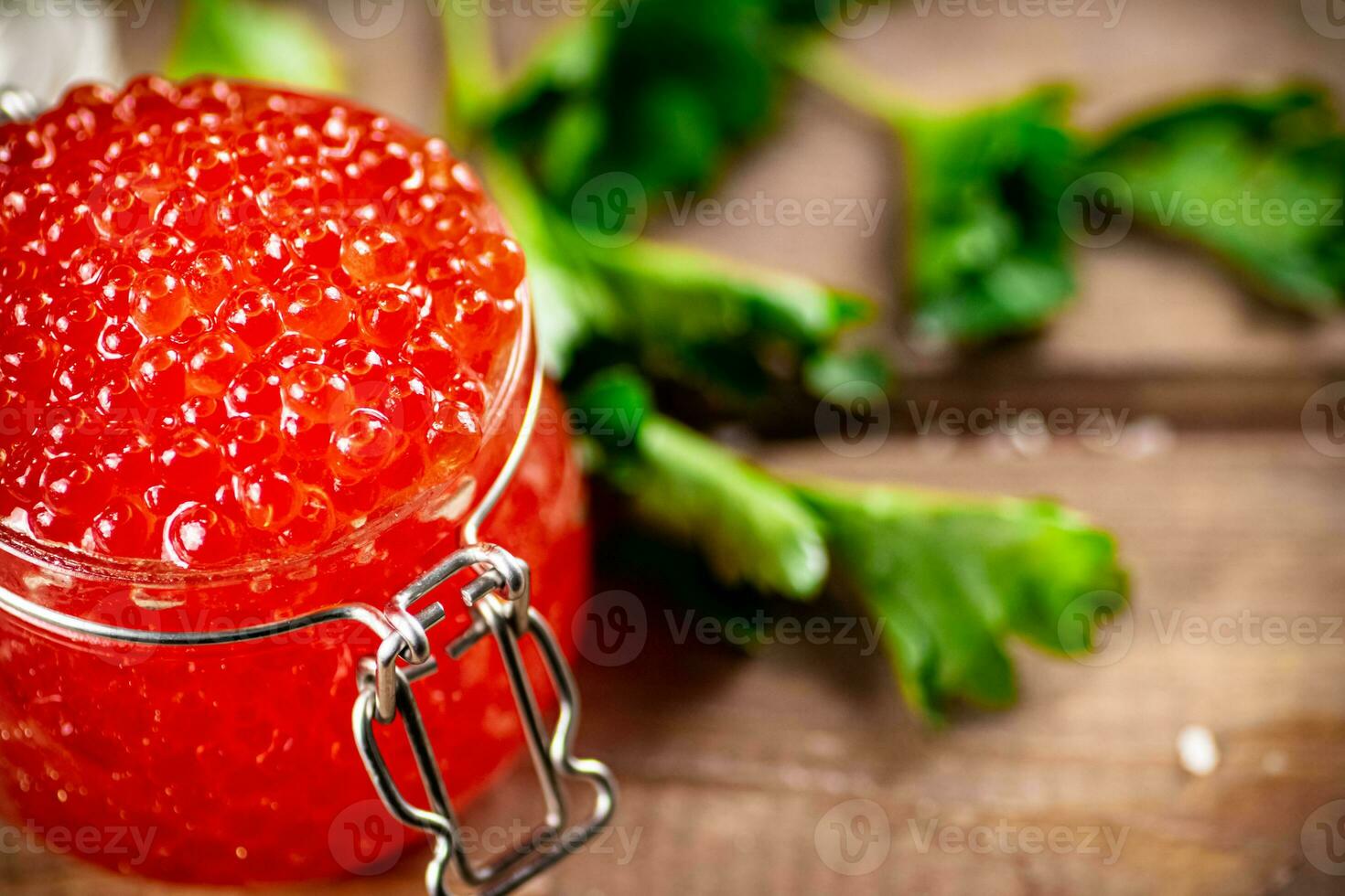 Red caviar in a glass jar with parsley. photo