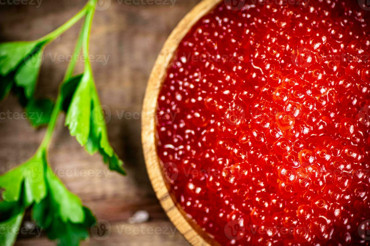 Red caviar in a plate on the table with parsley. photo