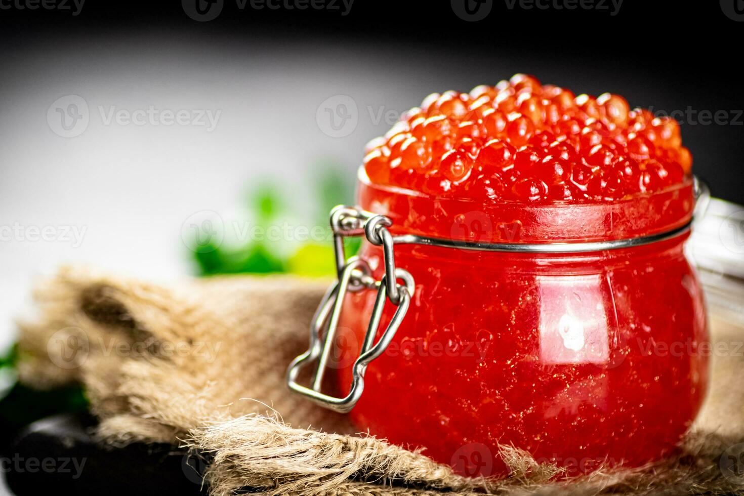 A glass jar with red caviar on burlap. photo