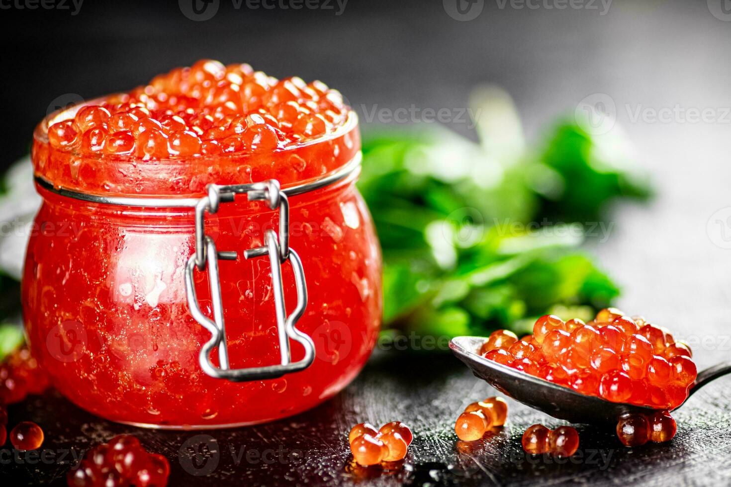 Red caviar in a glass jar with parsley. photo