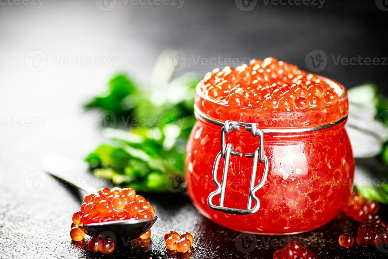 Red caviar in a glass jar with parsley. photo