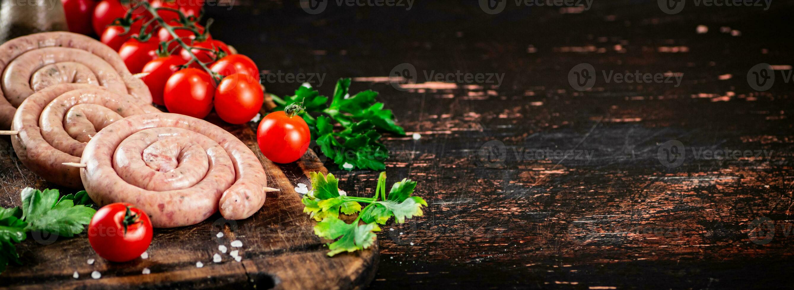 Round raw sausages with tomatoes and parsley. photo