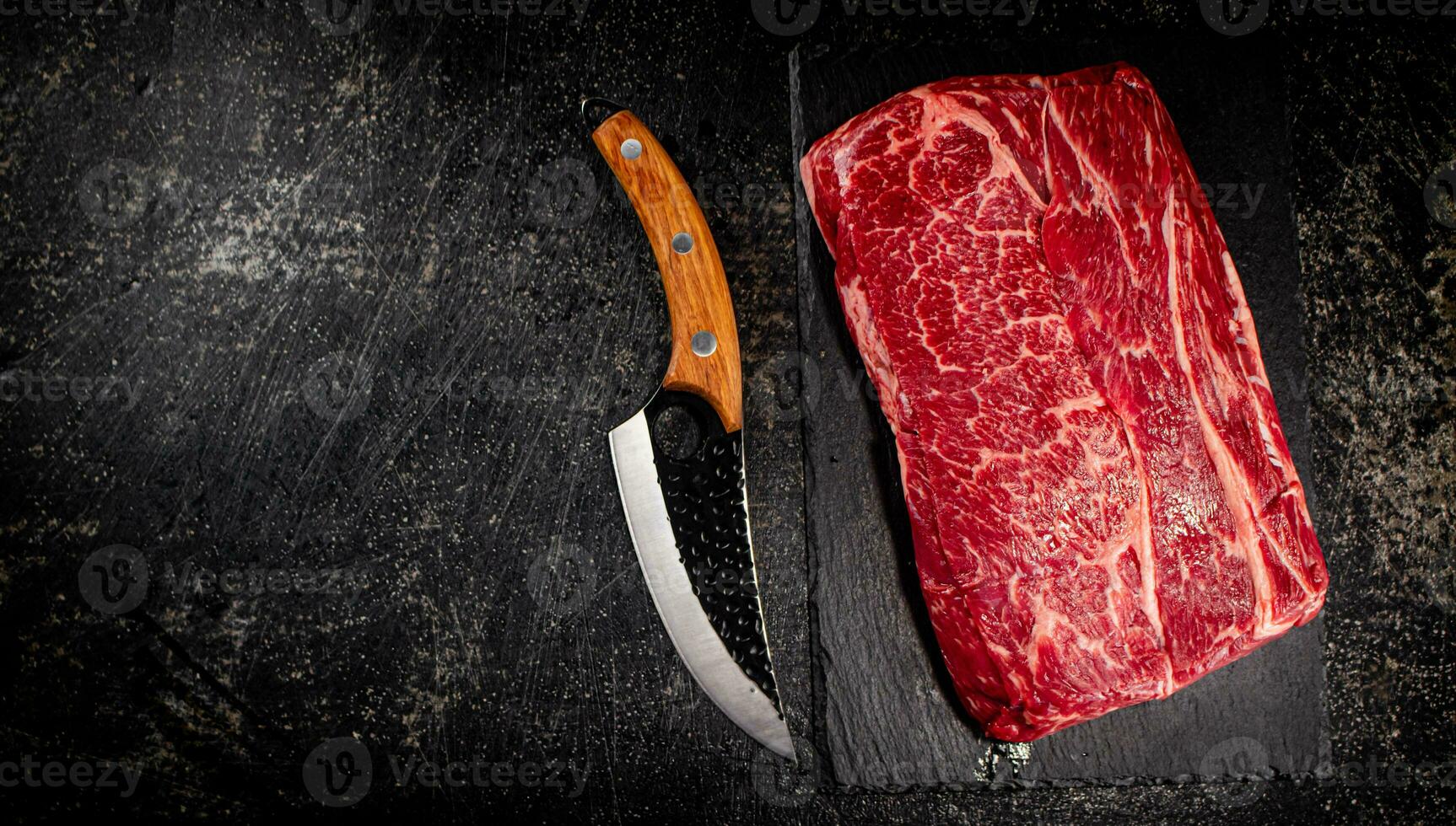 Raw beef on a stone board with a knife. photo